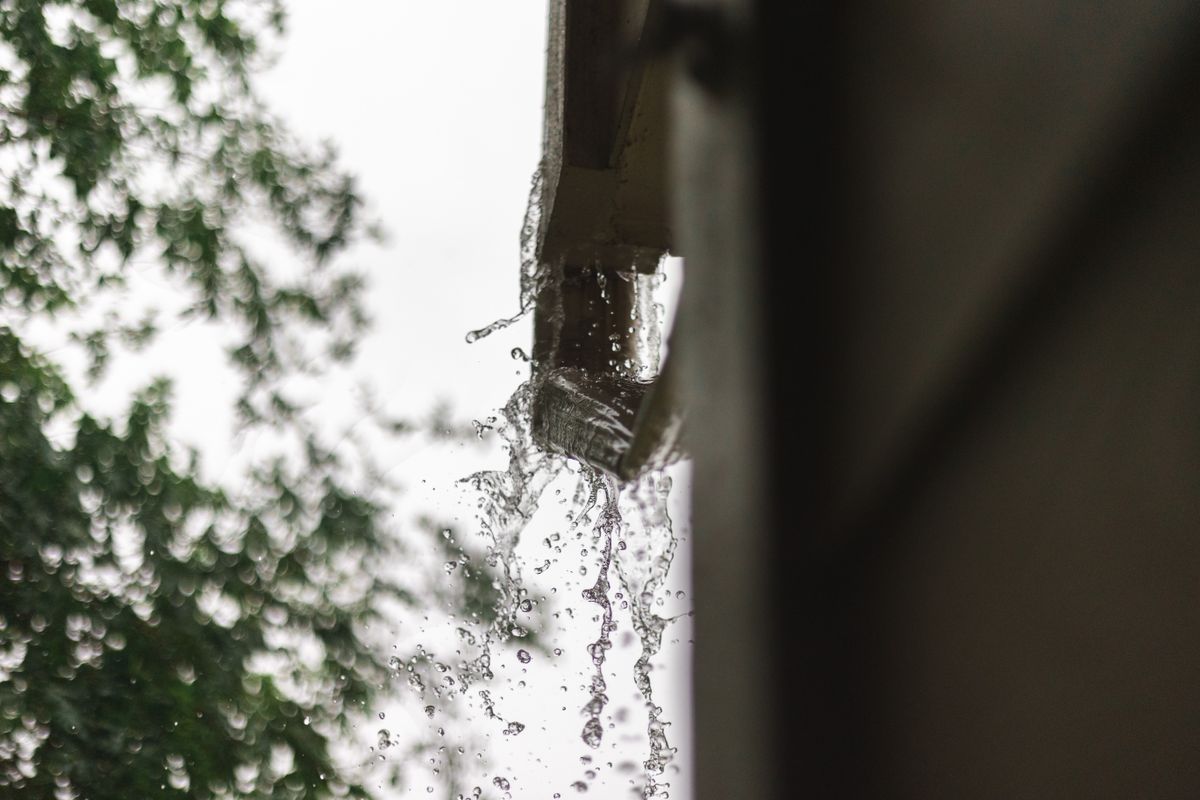 Rainwater spilling from the end of a roof gutter